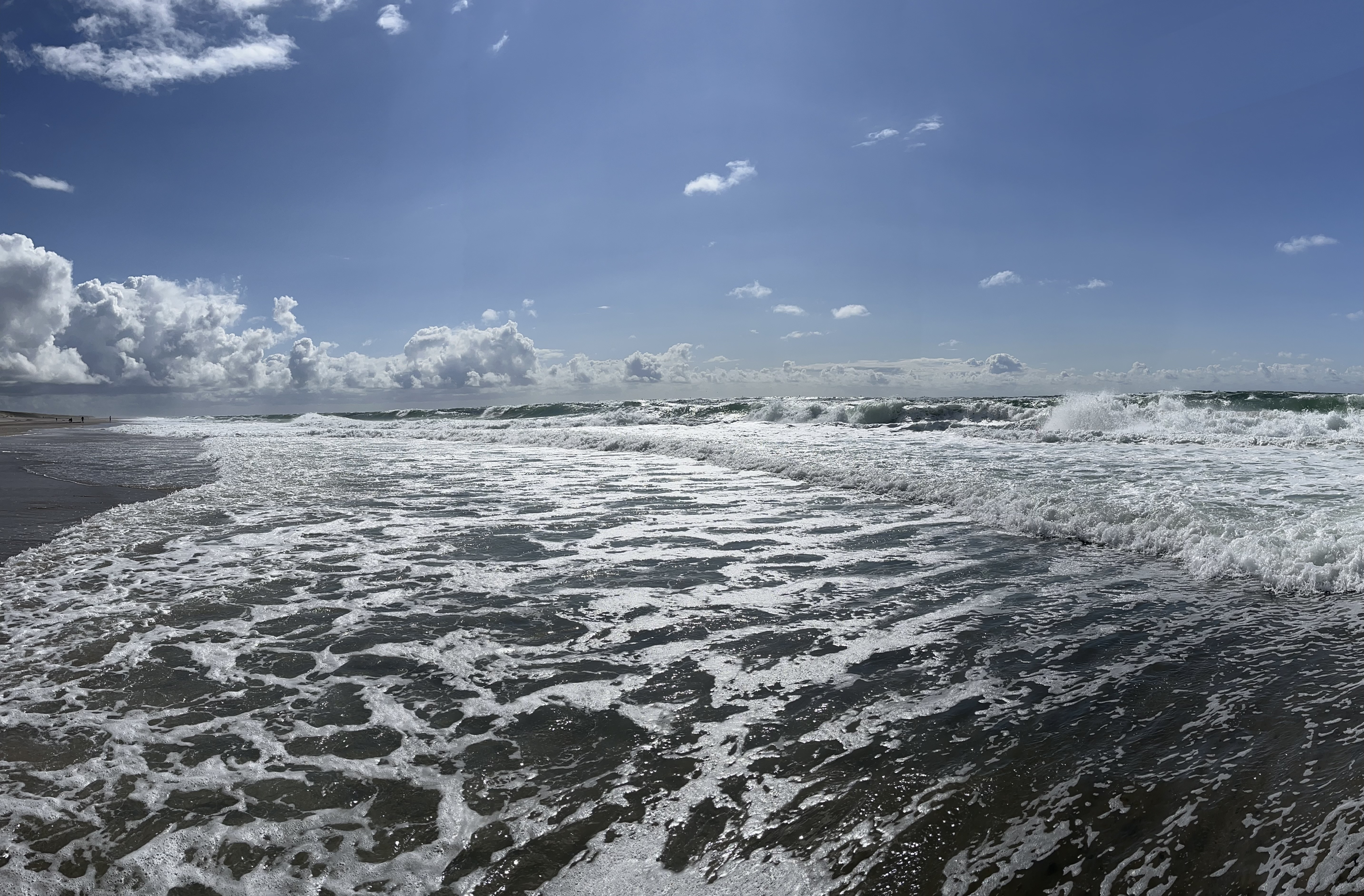 Das Bild &ldquo;Schöner Tag an der Nordsee&rdquo; entführt den Betrachter in eine idyllische Küstenlandschaft, die von friedlicher Gelassenheit und beeindruckender Naturschönheit geprägt ist. Die Nordsee erstreckt sich majestätisch bis zum Horizont, wobei das klare, azurblaue Wasser sanft an den weichen Sandstrand schwappt. Der strahlend blaue Himmel wird von einigen lockeren, weißen Wolken durchzogen und spiegelt sich harmonisch im glitzernden Wasser wider. Die Sonne steht hoch am Himmel und strahlt mit ihrer warmen, goldenen Pracht, die den gesamten Strand in ein sanftes Licht taucht. Am Ufer entlang zieht sich eine malerische Promenade, gesäumt von charakteristischen Strandkörben, die einladend zum Verweilen einladen. Urlauber und Einheimische flanieren entspannt entlang des Strandes und genießen die belebte, aber dennoch ruhige Atmosphäre. Kinder bauen eifrig Sandburgen, während Möwen elegant über den Wellen kreisen und nach einem Leckerbissen Ausschau halten. Im Hintergrund erheben sich sanft geschwungene Dünen, deren Grasflächen in einem satten Grün erstrahlen und sich perfekt in die malerische Kulisse einfügen. Diese Dünen dienen nicht nur als Schutz vor Sturmfluten, sondern verleihen der Landschaft auch eine besondere Natürlichkeit und Authentizität. Der Gesamteindruck des Bildes ist geprägt von Harmonie und Gelassenheit. Es vermittelt das Gefühl eines perfekten Tages an der Nordsee, an dem die Zeit stillzustehen scheint und man die Schönheit der Natur in vollen Zügen genießen kann. Ob man selbst schon einmal an der Nordsee war oder nur davon träumt, dieses Bild weckt Sehnsucht nach einem unvergesslichen Urlaub an einem Ort, der uns mit seiner Schönheit und Ruhe verzaubert. Es lädt ein, in Gedanken in diese wundervolle Szenerie einzutauchen und sich für einen Moment dem Alltag zu entziehen